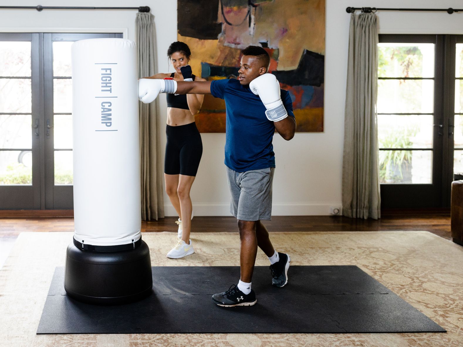 Man and woman punching FightCamp bag